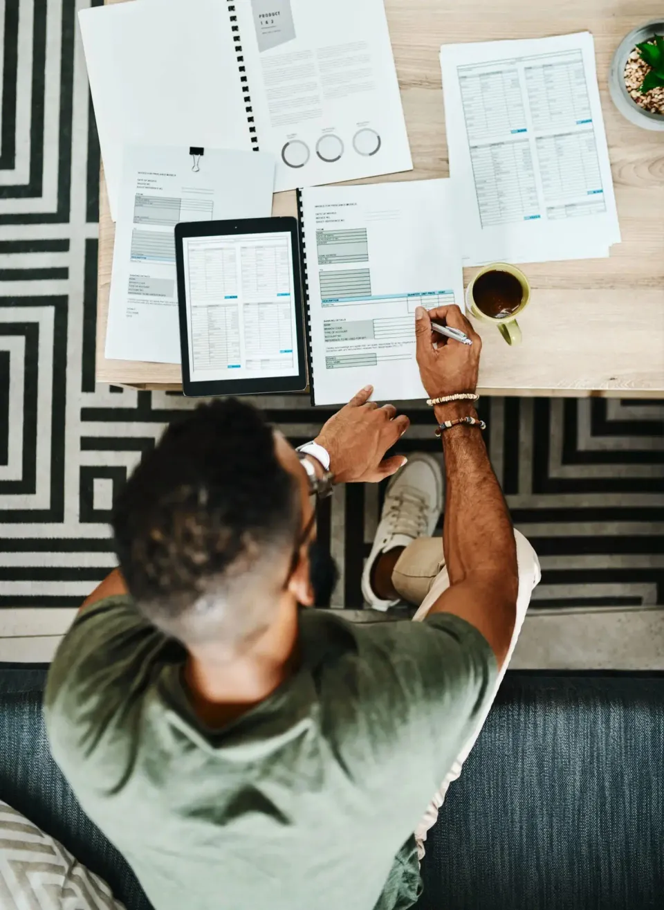 Vue de dessus d’une table de travail où un dirigeant annote une facture à côté d’une tablette